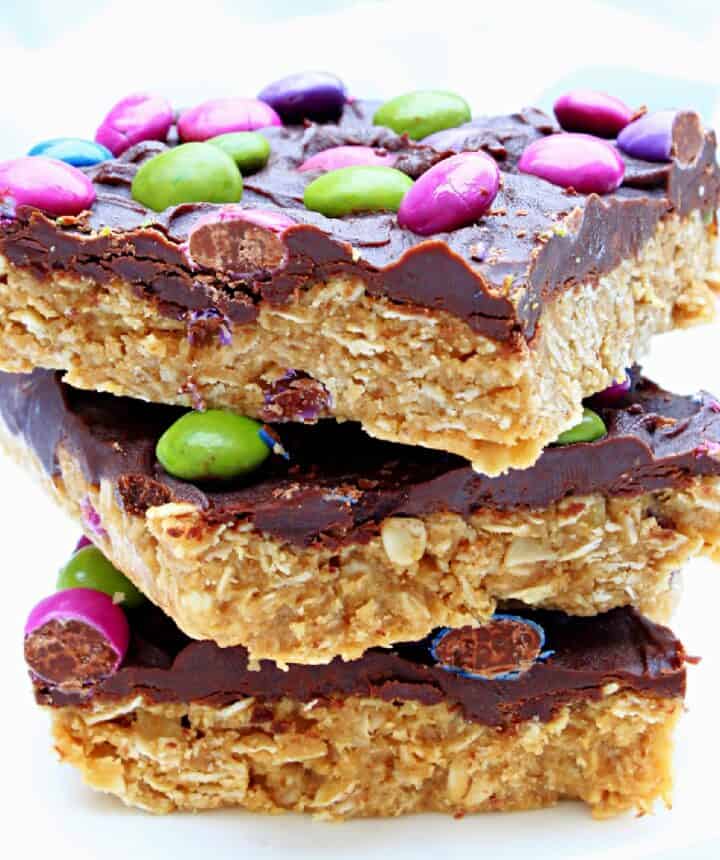 A stack of three cookie bars topped with chocolate and candy.