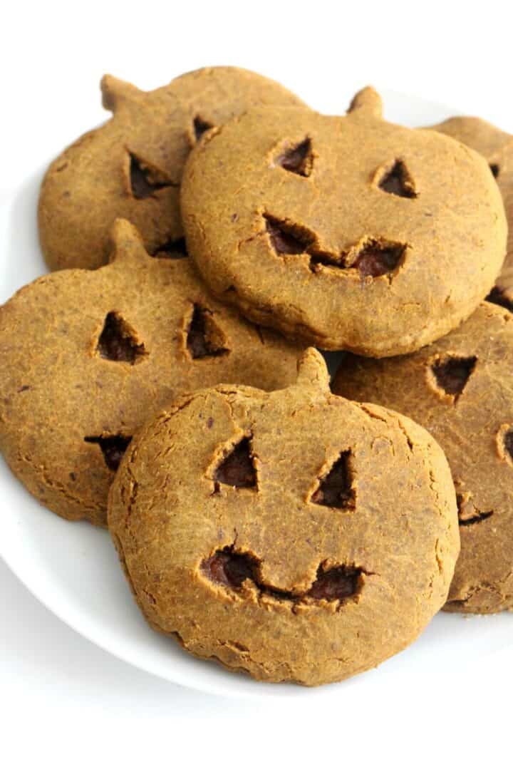 A pile of pumpkin shaped cookies on a plate.