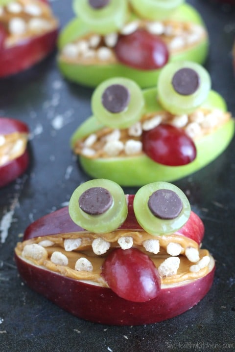 Apple slices and grapes cut to form silly monster faces.