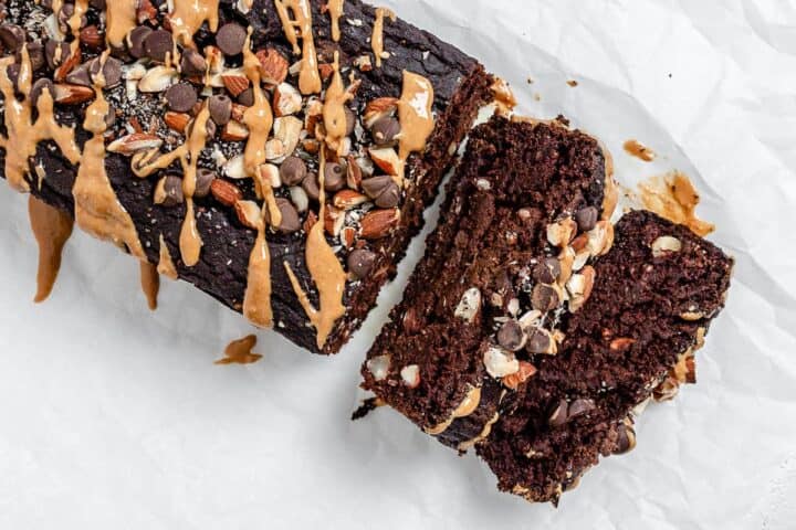 Two slices cut from a chocolate loaf cake topped with nuts.
