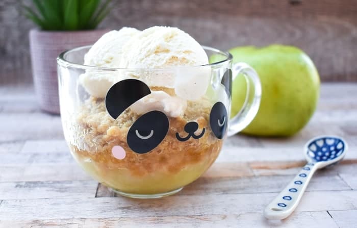 A microwaved apple crumble in a glass panda mug.