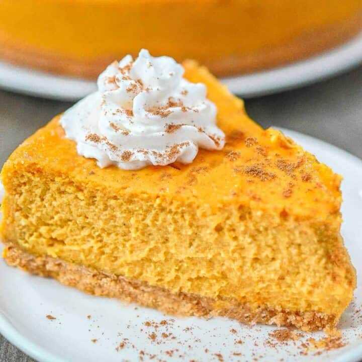 A slice of pumpkin cheesecake with a dollor of cream on top.
