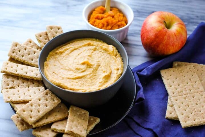 A bowl of pumpkin dip next to some crackers.