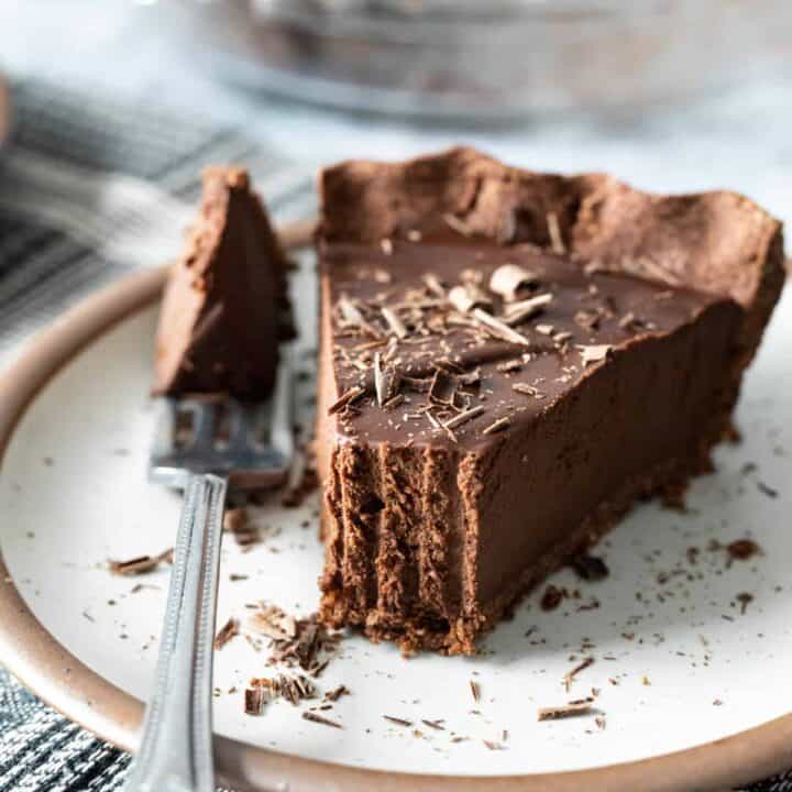 A fork has taken a bite from the end of a slice of chocolate pie.