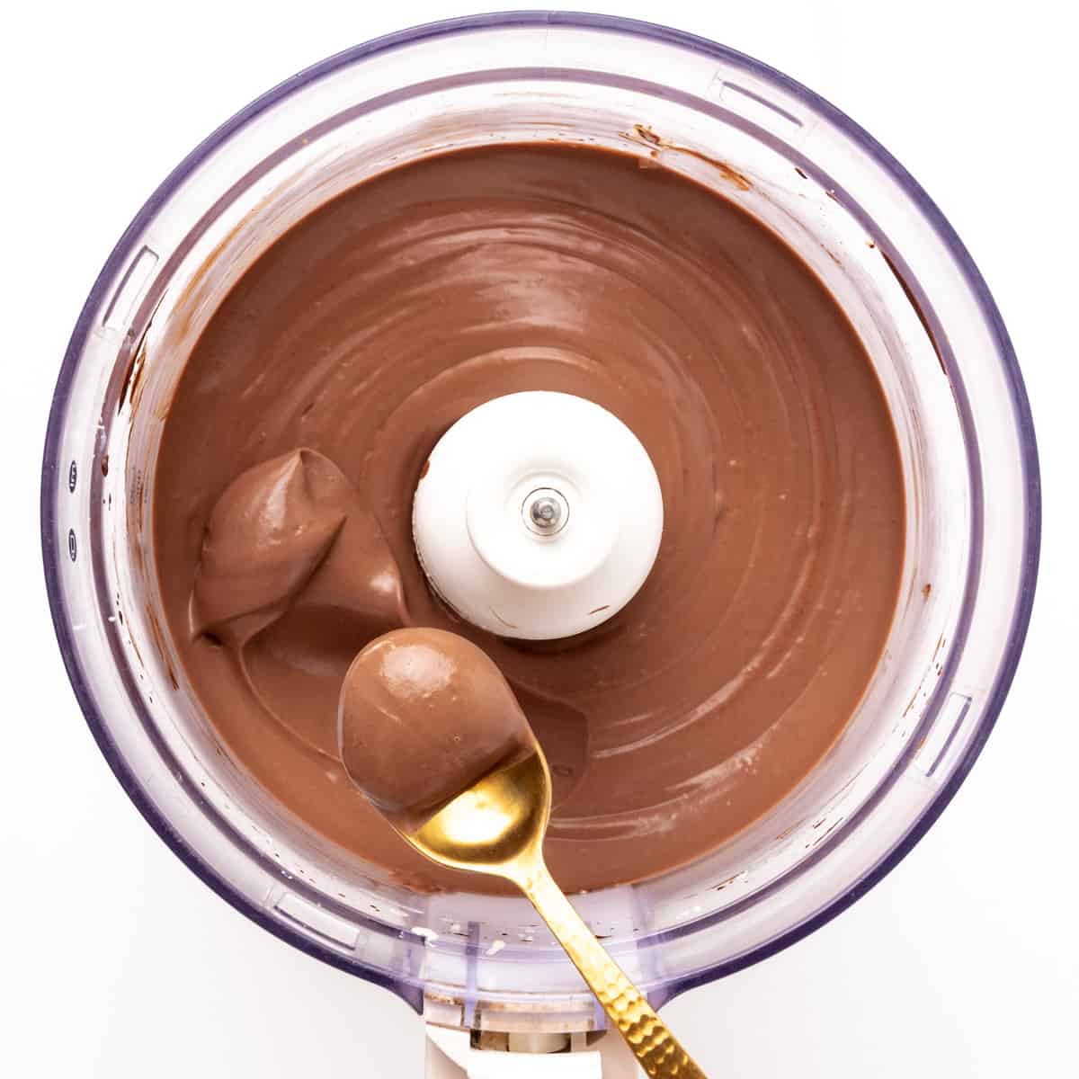A spoons scoops up mousse from a food processor.