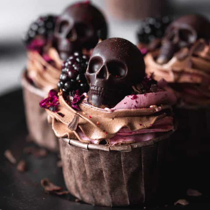 A cupcake decorated with chocolate and blackberry buttercream and a chocolate skull.