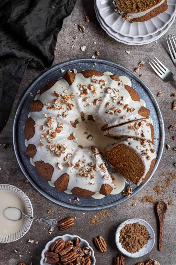 A bundt cake topped with icing and pecans.