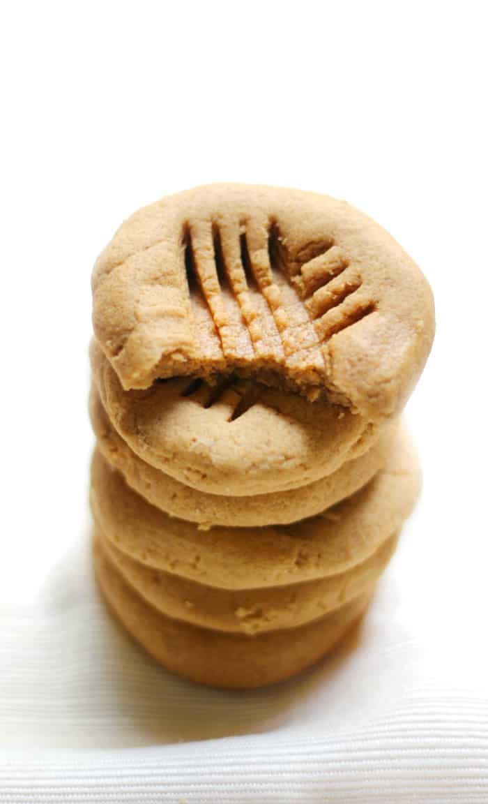 A stack of peanut butter cookies, the top one with a bite out.