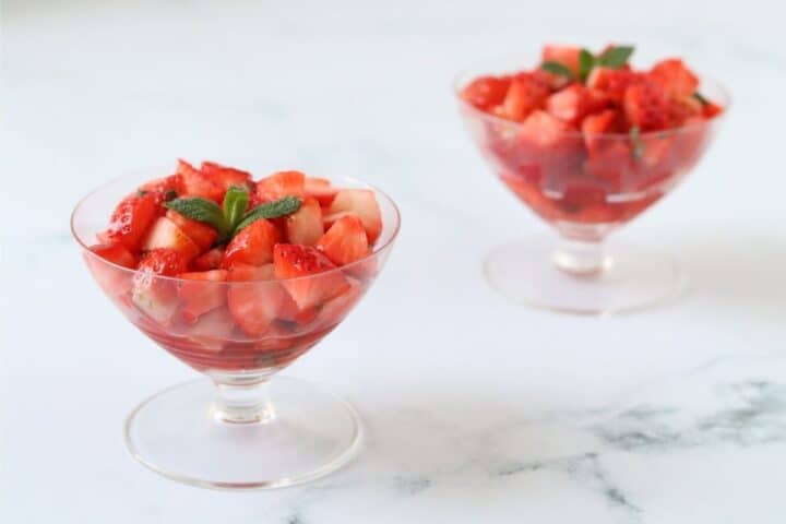Two glass dishes filled with strawberries and mint.