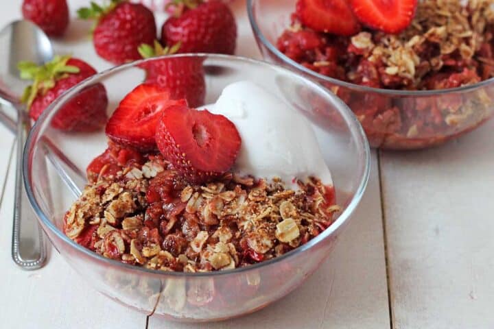 Two bowls with strawberry rhubarb crisp and ice cream.