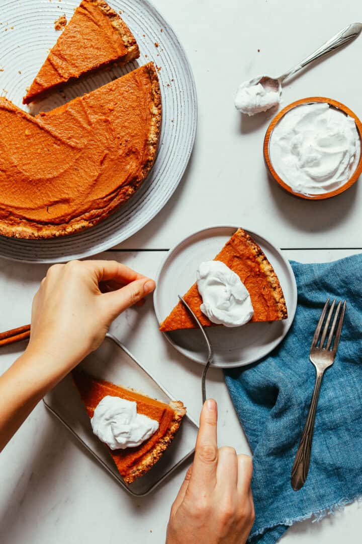Slices of pumpkin pie on plates, next to the remaing pie.