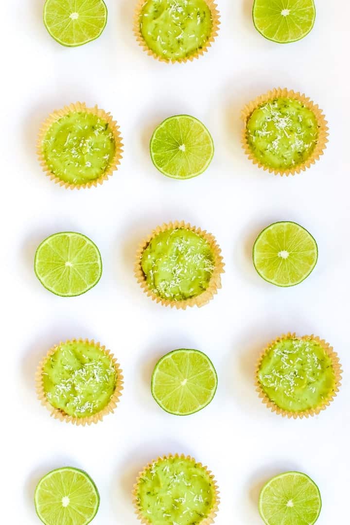 Mini lime pies arranged in a pattern with slices of lime.