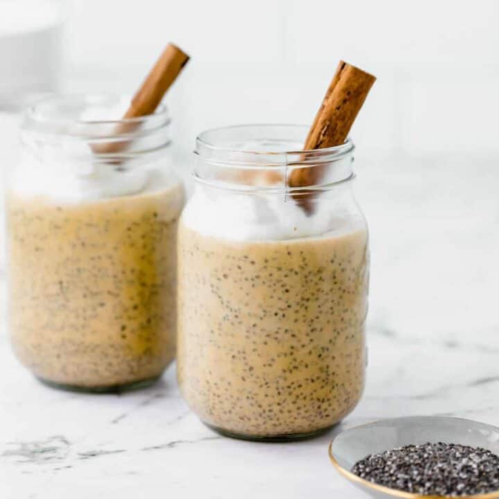Two jars of pumpkin chia pudding topped with a cinnamon stick.