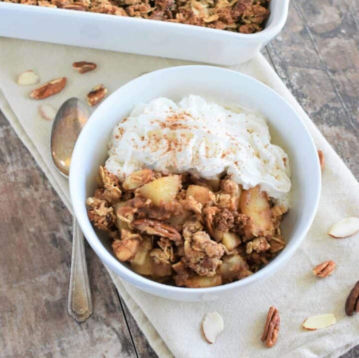 A bowl of pear crisp with whipped cream.