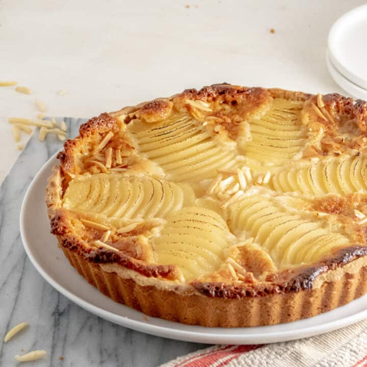 A tart topped with neatly sliced pears and almonds.