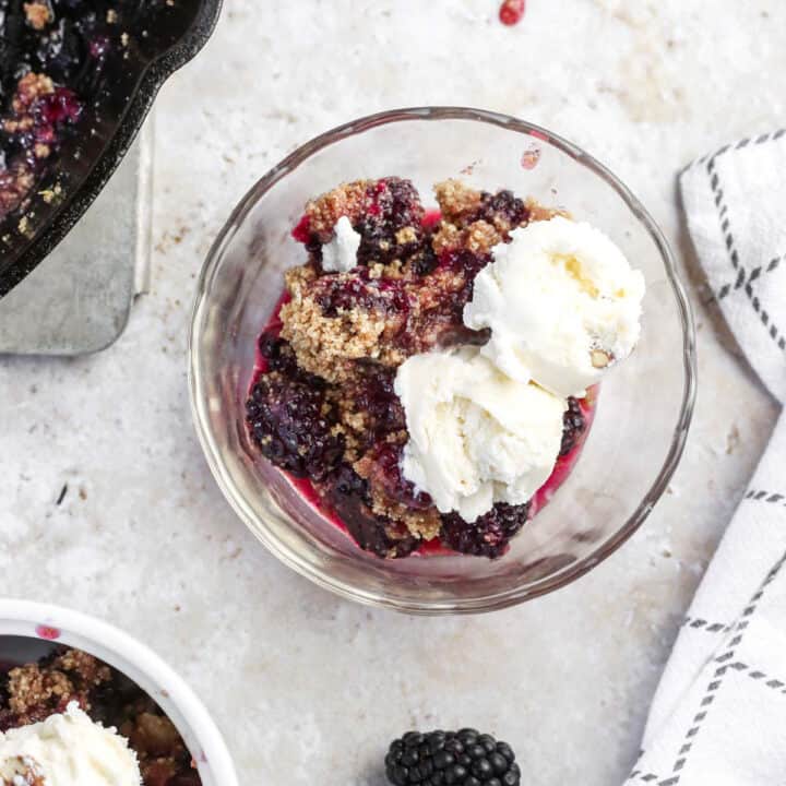 Blackberry crumble in a bowl topped with ice cream.