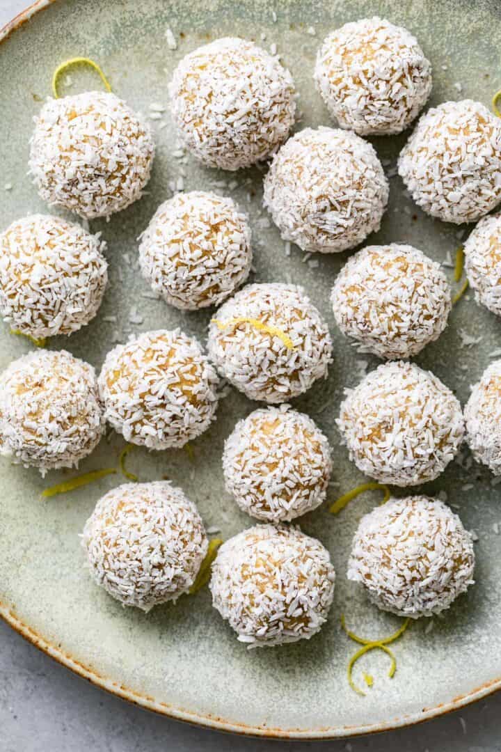 Balls coated in shredded coconut and drizzled in lemon zest on a plate.