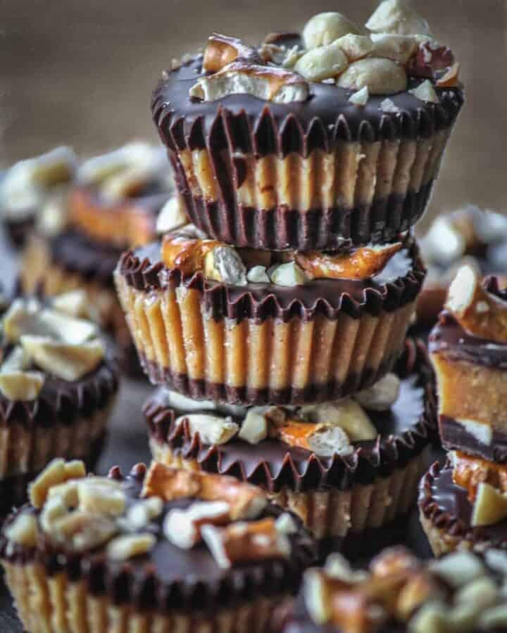 A pile of peanut butter cups topped with pretzels and nuts.