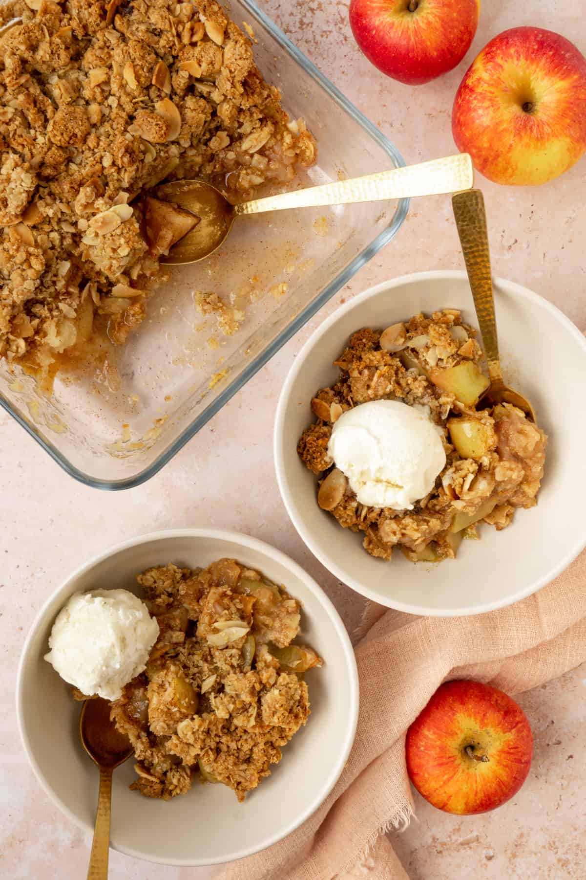 Two servings of GF apple crisp next to the remaining crisp in a dish.