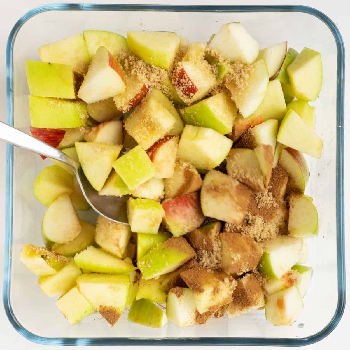 Diced apples with brown sugar and cinnamon in a baking dish.