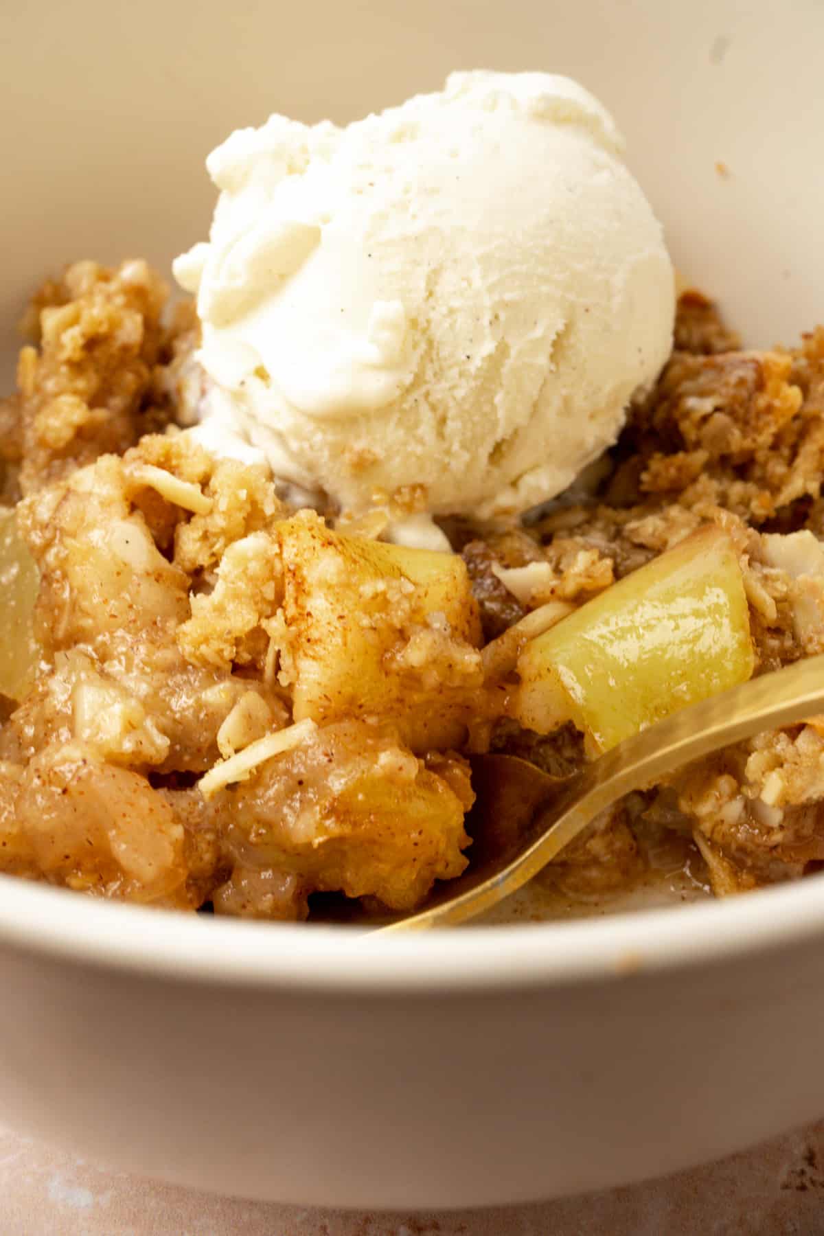 Juicy, cinnamony apples topped with streusel in bowl.