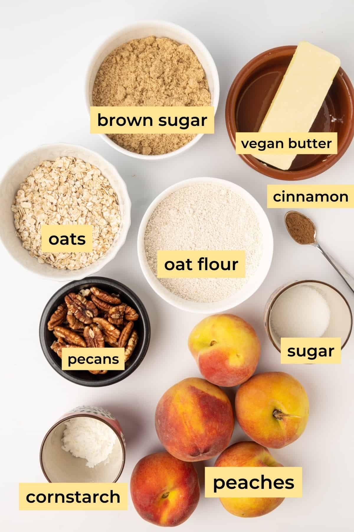 Ingredients for vegan peach crisp arranged on a white surface.