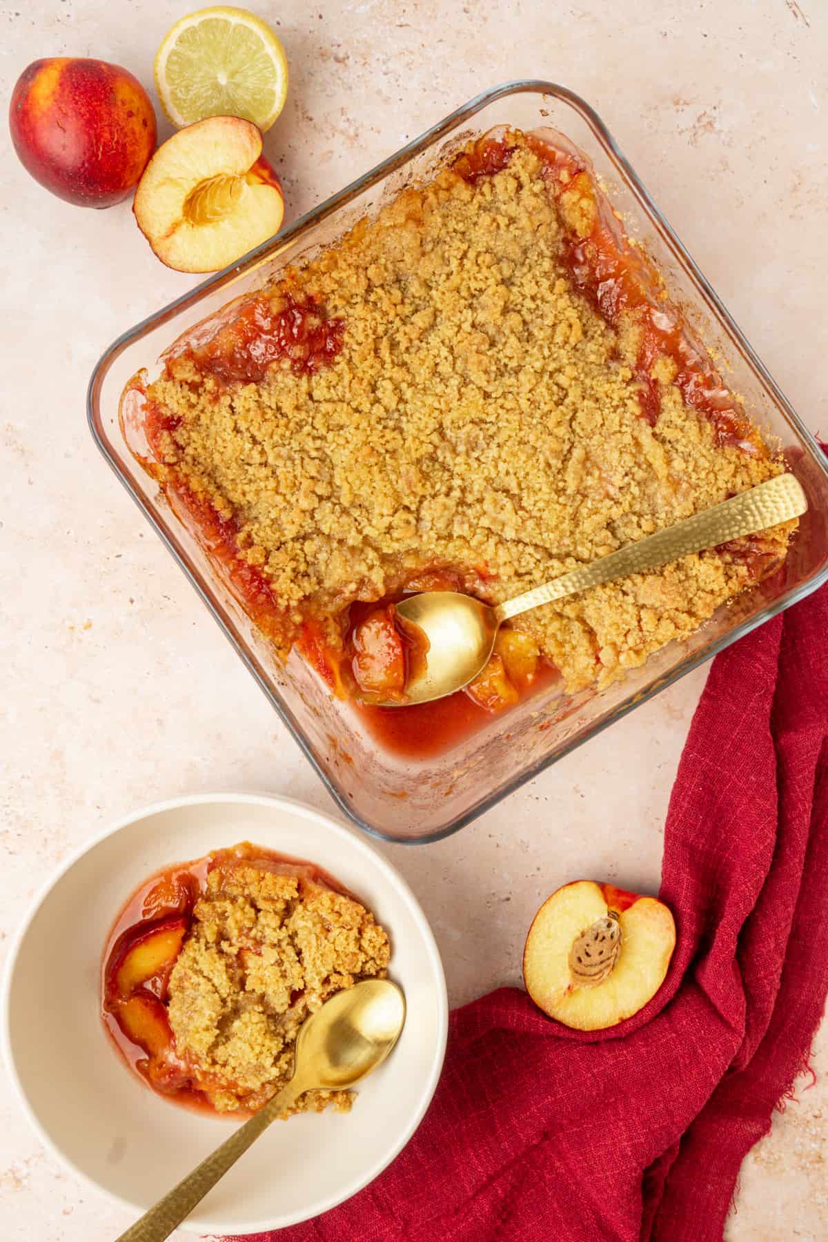A peach crumble in a baking dish and a portion in a bowl.