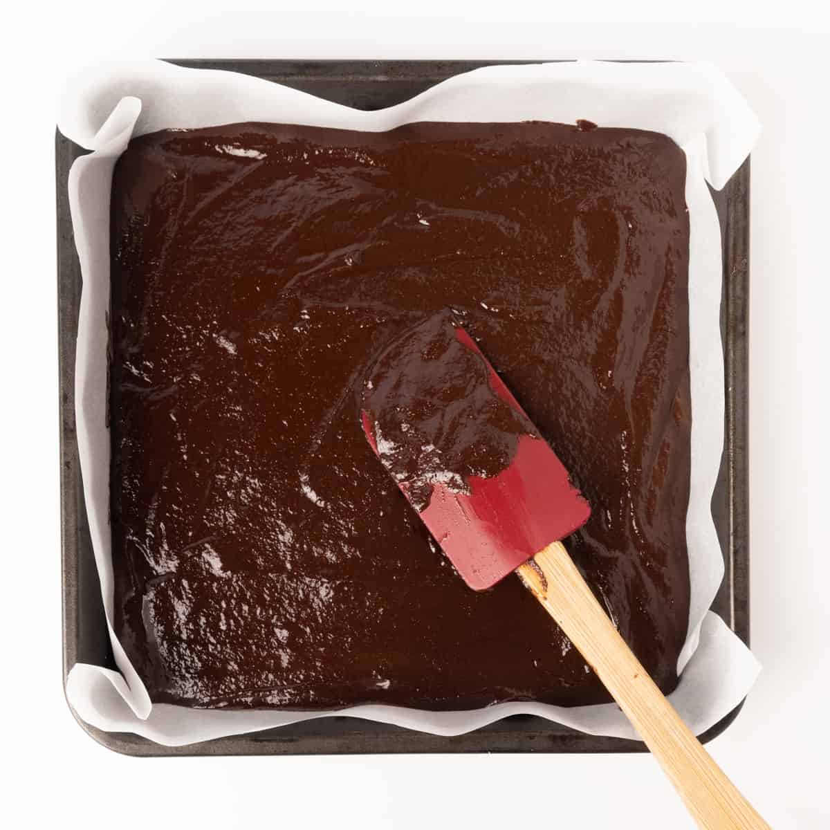 The warm fudge mixture spread out in a lined tray.