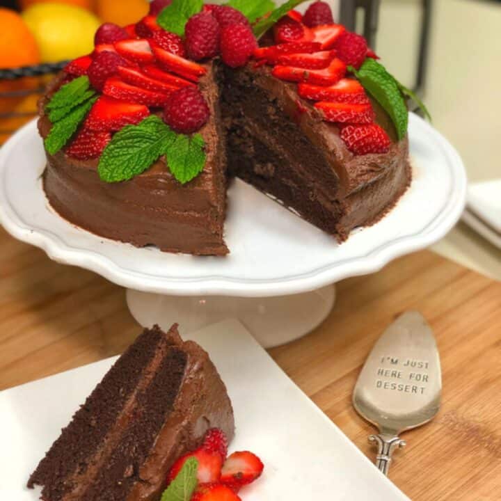 A chocolate cake decorated with chocolate buttercream, strabweeries, raspberries and mint leaves.