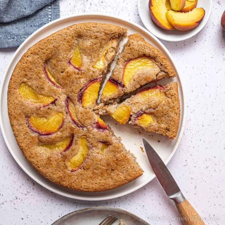 A cake with peach pieces in with two slices cut.