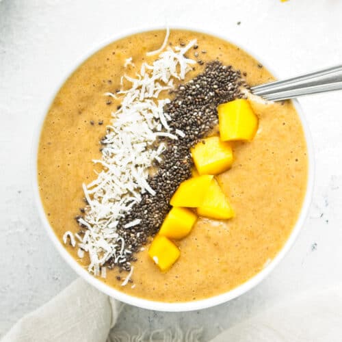 Mango, banana and orange smoothie bowl with a spoon in.