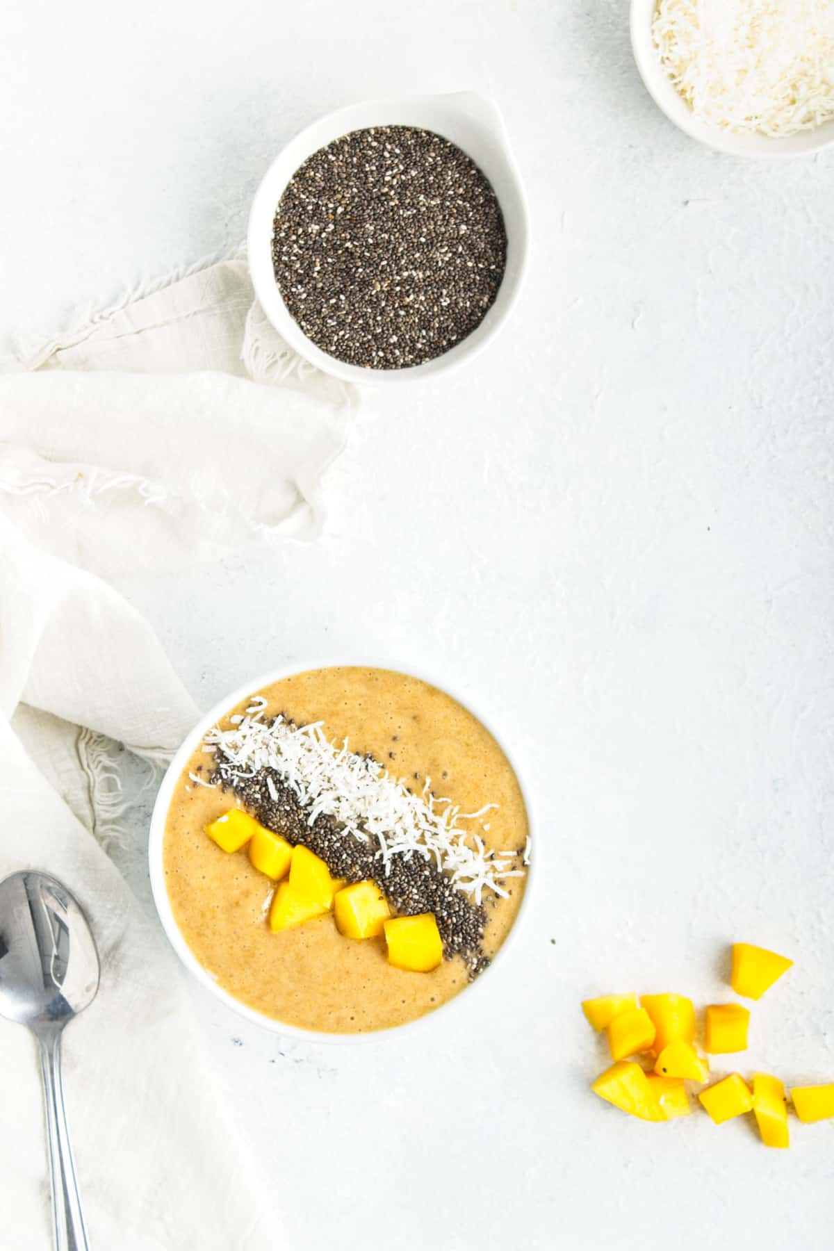 A smoothie bowl next to bowls of chia seeds and shredded coconut.