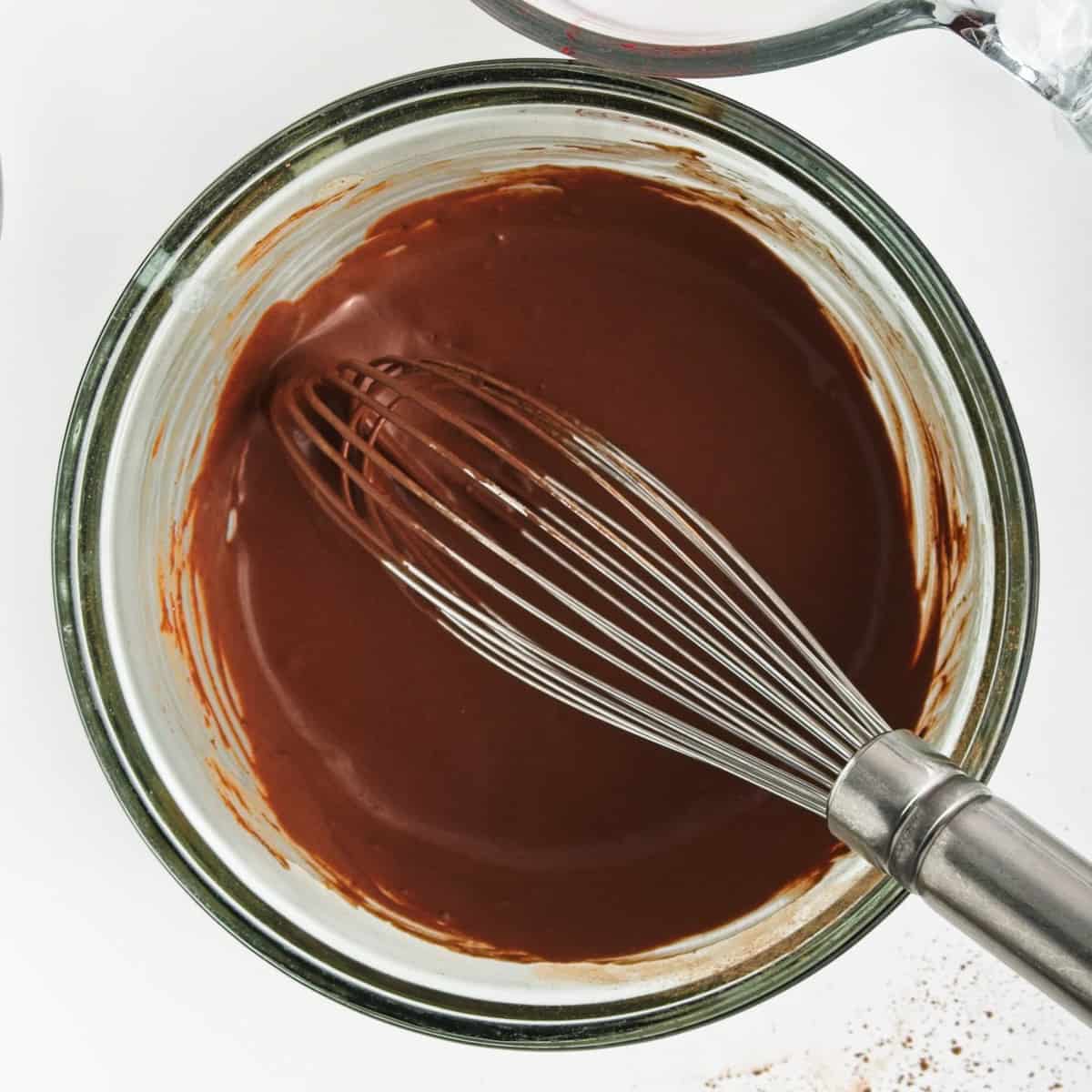 A thick chocolate and coconut milk paste in a bowl with a whisk.