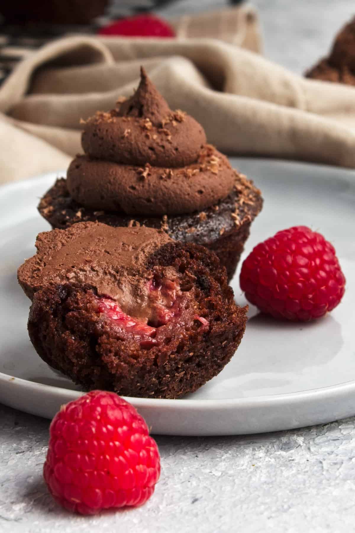 A cupcake cut in half revealing a juicy raspberry inside.