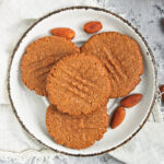 A pile of almond cookies on a plate.