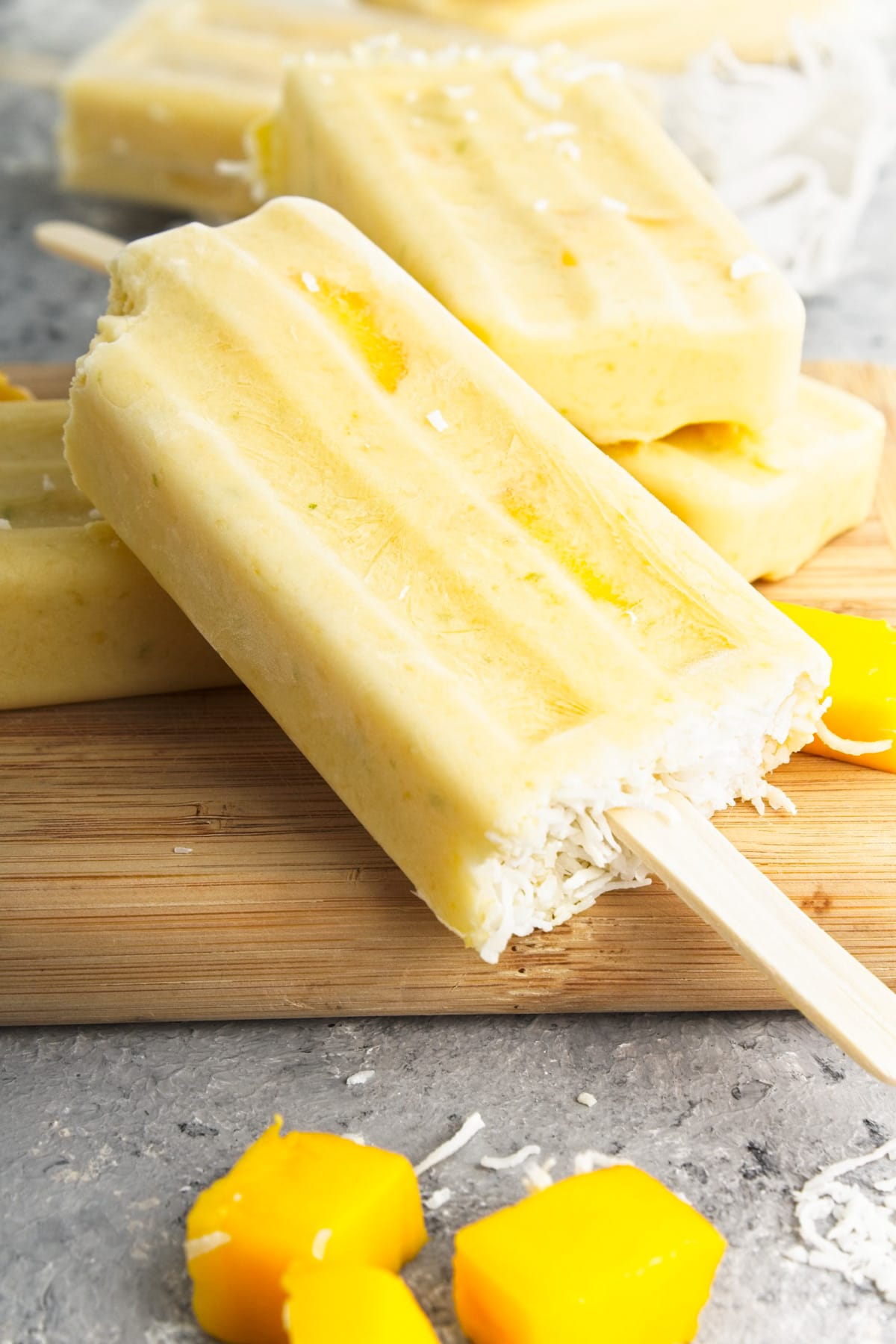 A coconut mango popsicle with a bite take out.