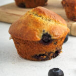 A golden brown muffin containing blueberries.