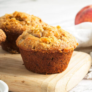 Vegan peach muffins topped with brown sugar.