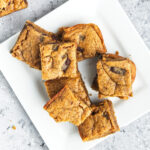 Pieces of peanut butter blondie on a square white plate.