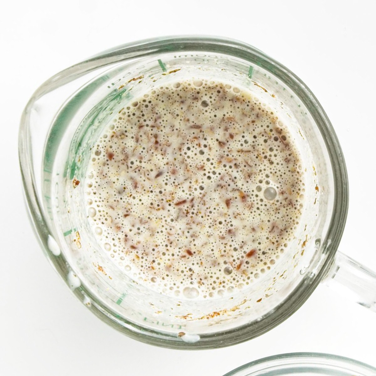 Oat milk and flaxseed in a measuring cup.
