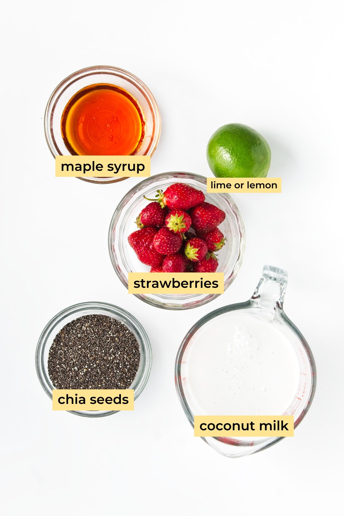 Ingredients in glass bowls: maple syrup, strawberries, lime, chia seeds and coconut milk.