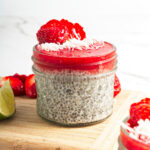A portion of strawberry chia pudding topped with coconut and sliced strawberry.