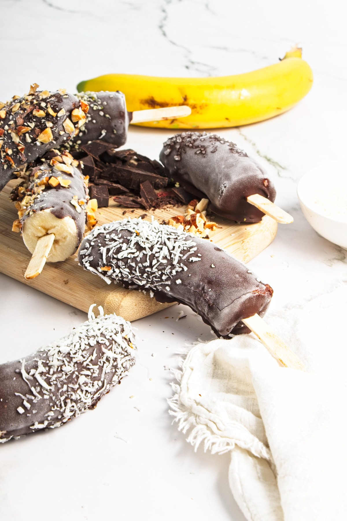 A variety of chocolate dipped bananas with a white cloth.