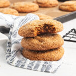 A stack of three chewy ginger cookies, the top one with a bite out.