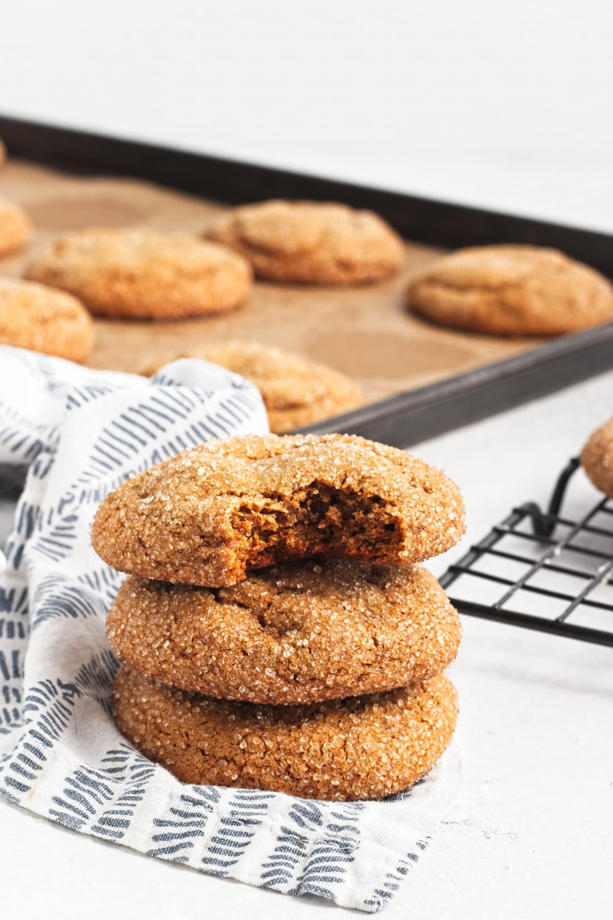 A stack of three chewy ginger cookies, the top one with a bite out.