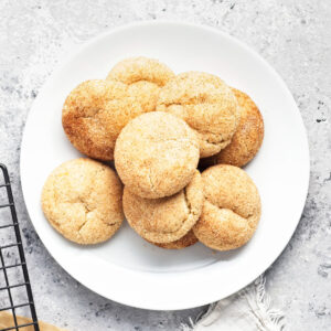 A pile of vegan snickerdoodle cookies on a white plate.